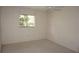 Simple bedroom with neutral walls, carpet, ceiling fan, and window overlooking greenery at 12371 Dearborn Dr, Hudson, FL 34667