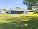 Spacious backyard view of a single-story home featuring a screened lanai and green grass at 13010 Siam Dr, Spring Hill, FL 34609