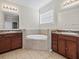 Bright bathroom featuring double sink vanity and a soaking tub with tile surround at 13366 Barkingside Pl, Spring Hill, FL 34609