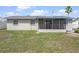 Exterior rear view showcasing a screened lanai, providing an inviting outdoor space with a lush lawn at 13700 Allyn Dr, Hudson, FL 34667