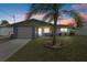 Charming single-story home with blue accents, front lawn, and mature palm tree at dusk at 13700 Allyn Dr, Hudson, FL 34667