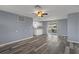 Spacious living area featuring grey toned wood flooring, an airy ceiling fan, and white cabinets at 13700 Allyn Dr, Hudson, FL 34667