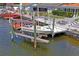 Waterfront boat dock with boat lift, and a waterfront seating area under a blue sky at 15635 Bertram Dr, Hudson, FL 34667