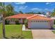 Single-story house showcasing a red tile roof, palm tree, manicured lawn and attached two-car garage at 15635 Bertram Dr, Hudson, FL 34667