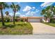 Inviting single-story home with a tile roof, a two-car garage, and lush landscaping at 15635 Bertram Dr, Hudson, FL 34667