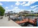 Waterfront featuring boat lifts, wooden dock, lush landscaping, and canal views under a bright sky at 15635 Bertram Dr, Hudson, FL 34667