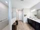 Bright bathroom features a glass-enclosed shower, double vanity with modern fixtures, and wood-look flooring at 19879 Tattnall Way, Brooksville, FL 34601