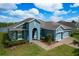 Beautiful single-story home with a three-car garage, blue exterior paint, and a well-maintained lawn at 19879 Tattnall Way, Brooksville, FL 34601