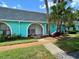 Inviting turquoise condo featuring an arched entryway, mature palms, and well-maintained landscaping at 4217 Terrapin Pl # 4217, New Port Richey, FL 34652
