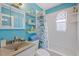 Bright blue bathroom with a shower/tub combination and ample storage shelves at 4400 Floramar Ter, New Port Richey, FL 34652