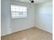 Cozy bedroom with tile floors, a ceiling fan, and bright natural light through the window at 4945 Getner St, New Port Richey, FL 34652