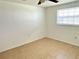 Bright bedroom featuring tile floors, a ceiling fan, and natural light streaming through the window at 4945 Getner St, New Port Richey, FL 34652