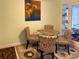 Cozy dining area features a round glass table, four floral upholstered chairs, and a colorful painting at 5406 Dartmouth Rd, New Port Richey, FL 34652
