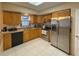 Bright kitchen featuring wooden cabinets, stainless steel appliances, tile floors, and a window above the sink at 5406 Dartmouth Rd, New Port Richey, FL 34652
