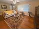 Bright living room with hardwood floors, plush sofa, ceiling fan, and natural light through large windows at 5406 Dartmouth Rd, New Port Richey, FL 34652