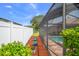 A fully fenced backyard features green lawn and a pool with screened enclosure at 5411 Wellfield Rd, New Port Richey, FL 34655