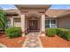 Charming covered front entrance with a decorative walkway and landscaped garden beds at 5411 Wellfield Rd, New Port Richey, FL 34655