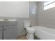 Bathroom features a gray vanity, toilet, and a bathtub under a bright window with light colored tile at 5651 Townhouse Dr # 5651, New Port Richey, FL 34652