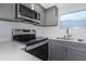 Modern kitchen featuring stainless steel appliances, gray cabinetry, and a bright window at 5651 Townhouse Dr # 5651, New Port Richey, FL 34652