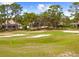 Beautiful green golf course with sand traps surrounded by tall trees at 5676 Legend Hills Ln, Spring Hill, FL 34609