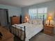 Cozy bedroom featuring a black metal bed frame, wood furnishings, and plenty of natural light from the window at 6516 Hillview Rd, Spring Hill, FL 34606