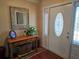 Inviting foyer with a decorative mirror, wood console table, and adjacent glass paneled front door at 6516 Hillview Rd, Spring Hill, FL 34606