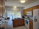 Well-lit kitchen featuring wood cabinets, white appliances, granite countertops, and a view of the backyard pool at 6516 Hillview Rd, Spring Hill, FL 34606