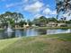 Picturesque community lake with a fountain, clubhouse, and lush landscaping on a sunny day at 6527 Spring Flower Dr # 24, New Port Richey, FL 34653
