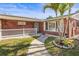 Charming brick home with a well-manicured lawn, walkway, and a decorative garden bed with palm trees at 6552 River Rd, New Port Richey, FL 34652