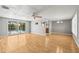 Bright living room with hardwood floors, a ceiling fan, and sliding glass doors overlooking the pool at 6552 River Rd, New Port Richey, FL 34652