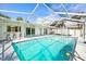 Sparkling pool with an enclosed screen, surrounded by a patio with barstools, perfect for outdoor relaxation at 6552 River Rd, New Port Richey, FL 34652