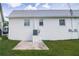 Back exterior showcasing the home's white walls, small patio, and well-maintained yard at 6710 Hickorywood Ln # 1B, New Port Richey, FL 34653