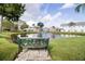 A tranquil community pond featuring a charming bench, fountain, and well-maintained landscaping at 6710 Hickorywood Ln # 1B, New Port Richey, FL 34653