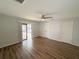 Bedroom with wood floors, ceiling fan, and a sliding glass door out to the lanai at 7026 Whitethorn Ct, Port Richey, FL 34668