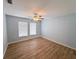 Bright bedroom with wood floors, ceiling fan, and natural light from two windows at 7026 Whitethorn Ct, Port Richey, FL 34668