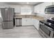 Bright kitchen with granite countertops, stainless appliances, white cabinets and gray wood-look flooring at 7026 Whitethorn Ct, Port Richey, FL 34668