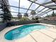 Enclosed backyard pool featuring clear blue water, a screened enclosure, and a spacious surrounding patio at 7026 Whitethorn Ct, Port Richey, FL 34668