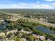 Aerial view featuring a community near a highway, showcasing ponds and commercial areas amidst lush vegetation at 7522 Heather Walk Dr, Weeki Wachee, FL 34613