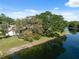 Waterfront home with lush trees offering shade, set beside a tranquil pond reflecting the sky at 7522 Heather Walk Dr, Weeki Wachee, FL 34613