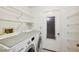 Efficient laundry room features a washer, dryer, ample shelving, and a convenient door to the outside at 7522 Heather Walk Dr, Weeki Wachee, FL 34613