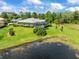 Aerial view of a house overlooking a lake; featuring a screened-in lanai/pool, lush lawns, and landscaping at 9032 Cypress Glen Ct, Weeki Wachee, FL 34613
