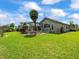 Spacious backyard with lush green lawn, mature landscaping, and a screened lanai for enjoying the outdoors at 9032 Cypress Glen Ct, Weeki Wachee, FL 34613