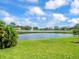 Scenic water view showcasing a serene lake, fountain feature, lush green lawn and a clear blue sky with fluffy clouds at 9032 Cypress Glen Ct, Weeki Wachee, FL 34613