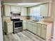 Well-lit kitchen with white cabinets, stainless steel appliances, and wood-look flooring at 9136 Mark Twain Ln, Port Richey, FL 34668