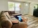 Bright living room featuring a comfortable sectional sofa, wood-look floors, and lots of natural light at 9136 Mark Twain Ln, Port Richey, FL 34668
