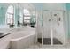 Bathroom featuring a soaking tub, a glass-enclosed shower, and large mirror for a relaxing and luxurious feel at 9301 Tournament Dr, Hudson, FL 34667