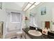 Bathroom features a shower with curtain, window, toilet, and sink with dark countertop and mirror at 9301 Tournament Dr, Hudson, FL 34667
