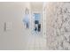 Hallway with decorative wallpaper, tiled floor, and light fixtures create an inviting transition space at 9301 Tournament Dr, Hudson, FL 34667