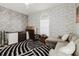 A home office with a black and white rug, gray couch, and unique wallpaper at 9301 Tournament Dr, Hudson, FL 34667