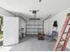 Open garage with a lawn mower, tools, a ladder, and ample storage space at 9316 Whitman Ln, Port Richey, FL 34668